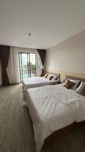 a hotel room with two beds and a large window at Moon Hotel Buôn Hồ in Buôn Tring
