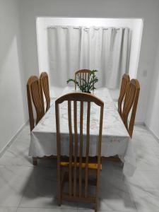 a dining room table with four chairs and a table with a plant on it at Casa de Maria Praia Suape in Cabo de Santo Agostinho