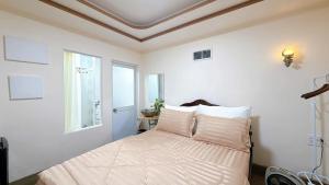 a bedroom with a bed with white sheets and a window at North House in Ấp Bình Trung
