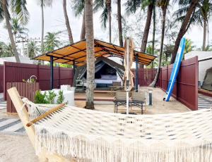 a hammock on the beach next to a surfboard at Sichon Glamping Resort, Beachfront in Ban Plai Thon