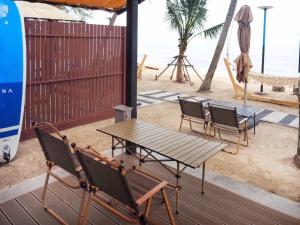 a picnic table and chairs on a beach with the ocean at Sichon Glamping Resort, Beachfront in Ban Plai Thon