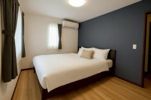 a bedroom with a bed with white sheets and pillows at Wstay in Ozu