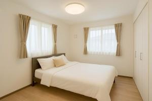 a bedroom with a white bed and two windows at Wstay in Ozu