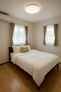 a large white bed in a room with windows at Wstay in Ozu