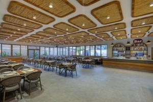 a dining room with tables and chairs and a bar at Monk Resort Hotel Beldibi in Kemer