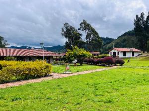 a yard with a house and a grass field at Posada de Aquilino MC in Cucunubá
