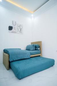 een bed met blauwe lakens in een witte kamer bij Pilla Villa Purwokerto in Purwokerto