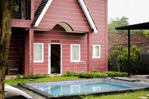 a red house with a swimming pool in front of it at Patria Villa Turi in Soprayan