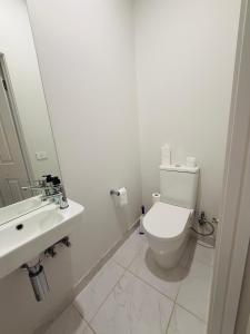 a white bathroom with a toilet and a sink at Peaceful Stay in Wyndham Vale