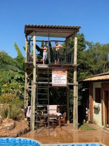 two men standing on a wooden tower next to a pool at Suíte master - Hostel em Itupeva in Itupeva