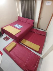 twee bedden in een kamer met rode en gele lakens bij Ambai Guest House in Kolhapur