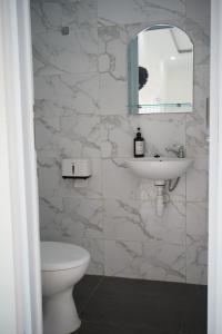 een badkamer met een wastafel, een toilet en een spiegel bij Pilla Villa Purwokerto in Purwokerto