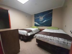 a room with two beds and a painting on the wall at El valle 2 in Copiapó