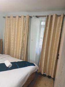 a bedroom with a bed and a window with curtains at Bliss Homes in Nairobi
