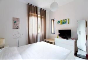una camera da letto bianca con un letto e una televisione di Nest Apollo a Mondello