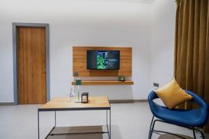 a living room with a table and a tv on a wall at Nes-Terns in Coimbatore