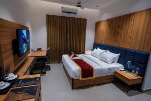 a bedroom with a bed and a desk and a television at Nes-Terns in Coimbatore