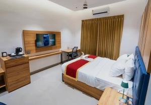 a hotel room with a bed and a television at Nes-Terns in Coimbatore