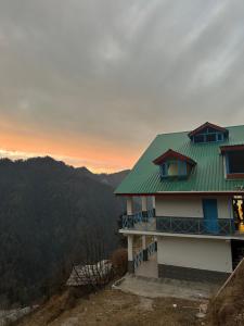 a house with a green roof on top of a hill at The Blue Mont Sojha Jibhi in Shoja