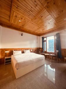 a bedroom with a large bed and a wooden ceiling at The Blue Mont Sojha Jibhi in Shoja