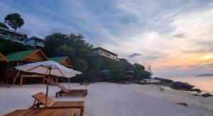 a beach with two benches and an umbrella at The Green Hotel in Ko Lipe