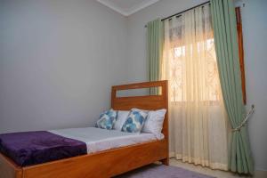 a bedroom with a bed and a window with curtains at Palm Haven Furnished Apartments in Bweyogerere