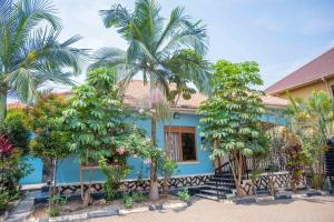a blue house with palm trees in front of it at Palm Haven Furnished Apartments in Bweyogerere