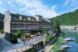 a building next to a river with boats in it at Phoenix Ancient Hill Riverside View Hotel- Offers free one-way high-speed rail pick-up service - Afternoon tea - Self-service laundry - Baggage storage - Travel planning in Fenghuang County