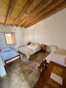 a bedroom with two beds and a wooden ceiling at Capec Alojamiento in Tilcara