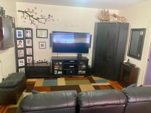 a living room with a couch and a flat screen tv at Woodside room in Sunnyside +3 photos