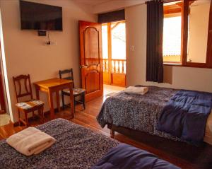 ein Schlafzimmer mit zwei Betten und einem Tisch und einem Balkon in der Unterkunft El Chasqui in Ollantaytambo + 30 Fotos