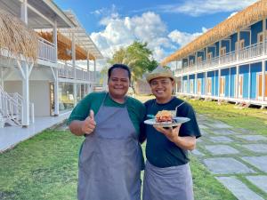 two men holding a plate of food in front of a building at The houmstay pangsing in Mataram