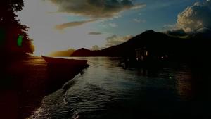 a boat in the water with the sun in the background at The houmstay pangsing in Mataram