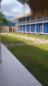 a blue building with a straw roof and a grass field at The houmstay pangsing in Mataram