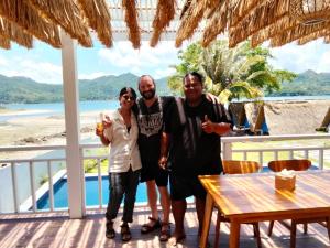 a group of three people standing on a porch at The houmstay pangsing in Mataram