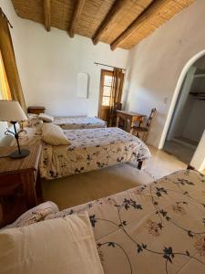 een slaapkamer met drie bedden en een tafel met een lamp bij Capec Alojamiento in Tilcara