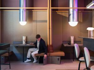 un uomo seduto a un tavolo con un portatile di You Hotel Budapest - Handwritten Collection a Budapest