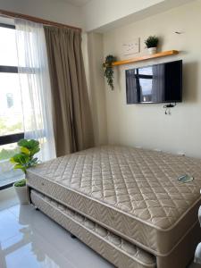 a bed in a bedroom next to a window at Mactan Plains condo unit in Punta Engaño
