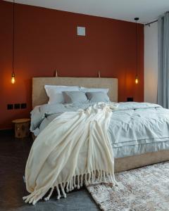 a bedroom with a large white bed with an orange wall at Ubuntu Residence in Ruhengeri