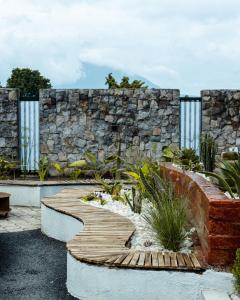 a garden with a wooden walkway in front of a stone wall at Ubuntu Residence in Ruhengeri