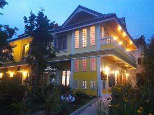 una casa amarilla con luces encendidas por la noche en Baan Bussaba Hotel, en Trang