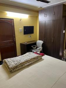 a bedroom with a bed and a desk and a tv at PlatinumIN Guesthouse in kolkata