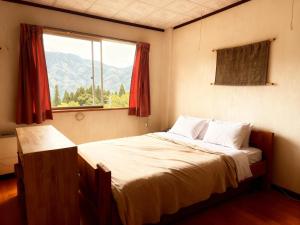 a bedroom with a large bed with a window at Kamoshika Lodge Hakuba in Minami Otari