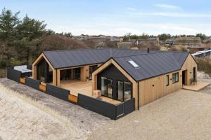 a large wooden house with a black roof at Feriehus 1147 in Ringkøbing