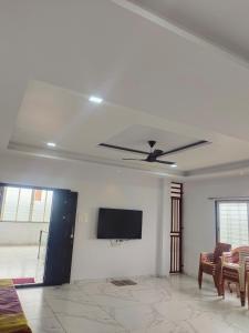 een woonkamer met een plafondventilator en een flatscreen-tv bij Fortress Homestay in Yavluj +28 foto's