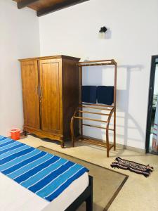 a room with a bed and a wooden cabinet at Pandula Villa 390 in Hikkaduwa