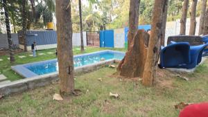 a swimming pool in a park with trees at Nishatana Farm Stay in Bangalore