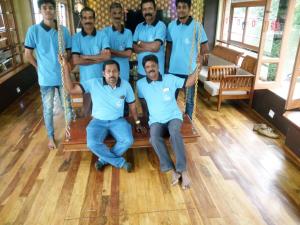 een groep mannen in blauwe shirts die op schommels zitten bij Kerala Nature Houseboat by Coco floatel in Alleppey