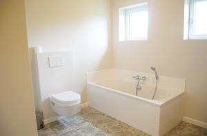 a white bathroom with a tub and a toilet at Vakantiehuis Hof te Voorde in Deerlijk