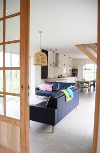 a living room with a blue couch and a kitchen at Vakantiehuis Hof te Voorde in Deerlijk